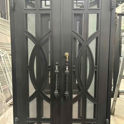A Premium Cast Iron Spiral Staircase by Like Metal features geometric and curved metalwork, glass elements, and ornate design details, showcased in an industrial workshop setting.