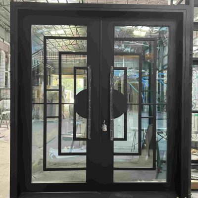 A Premium Cast Iron Spiral Staircase by Like Metal stands in a warehouse, its sleek black finish and elegant curves reflecting the surrounding glass doors and industrial structure above.