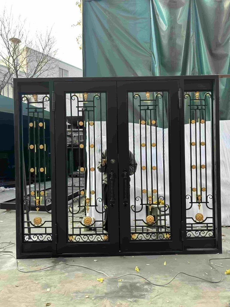 The Premium Cast Iron Spiral Staircases by Like Metal are shown outdoors. A person stands partly hidden behind the staircase, with a green tarp and building visible in the background. Black metal design with gold accents and intricate patterns is featured.