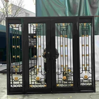 The Premium Cast Iron Spiral Staircases by Like Metal are shown outdoors. A person stands partly hidden behind the staircase, with a green tarp and building visible in the background. Black metal design with gold accents and intricate patterns is featured.