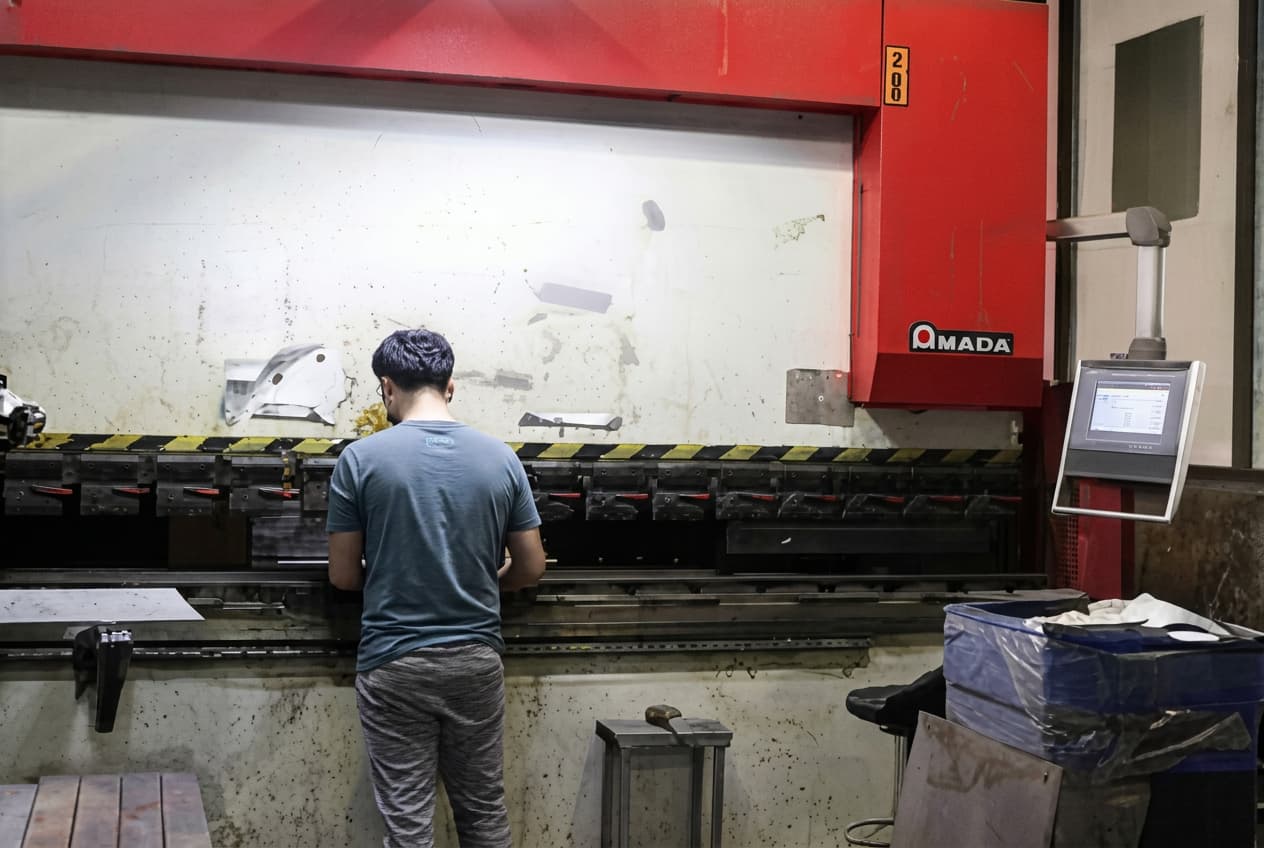 LIKE Metal CNC machining production line for table legs featuring automated milling centers, precision drilling stations, and robotic material handling systems, with skilled technicians monitoring computer control panels as high-quality metal table legs are precision-machined in a continuous flow manufacturing process.