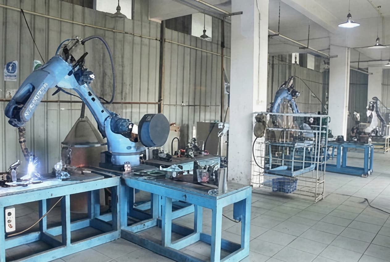 LIKE Metal factory using an advanced robotic welding arm to precisely weld metal table legs on an automated production line, with bright welding arcs, safety shielding, and quality control monitoring ensuring consistent, strong joints for high-volume table leg manufacturing.